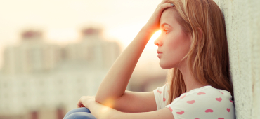 Fatigue eller trötthet. Kvinna sitter med ryggen mot en vägg.